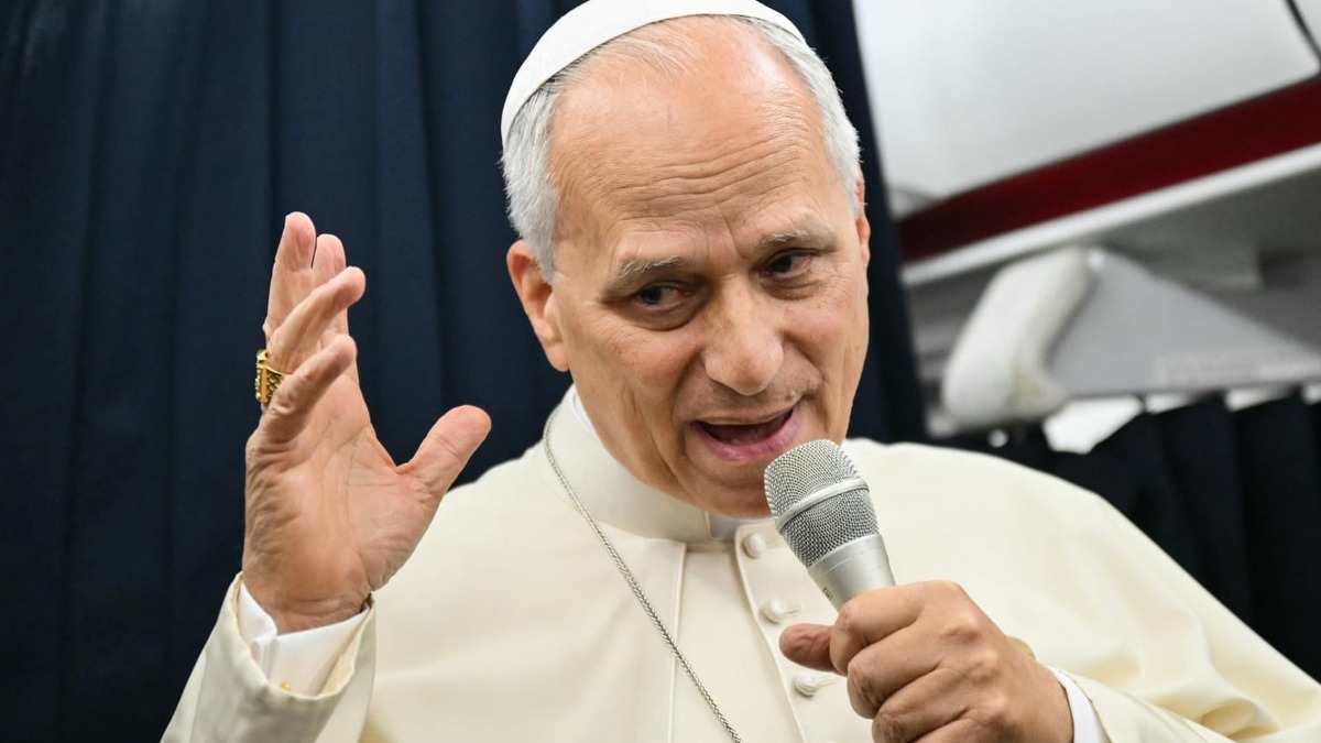 Pope Leo XIV speaking into a microphone aboard the papal plane returning from France