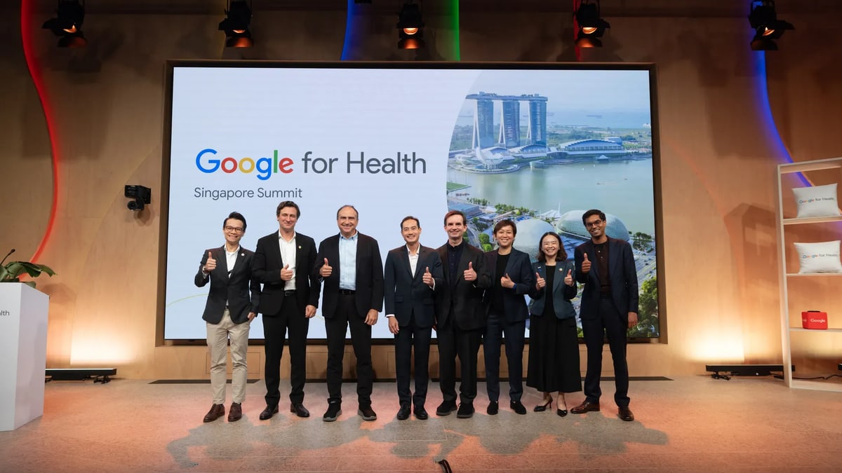 Eight speakers give a thumbs-up on stage at the Google for Health Singapore Summit, in front of a screen showing the Singapore waterfront