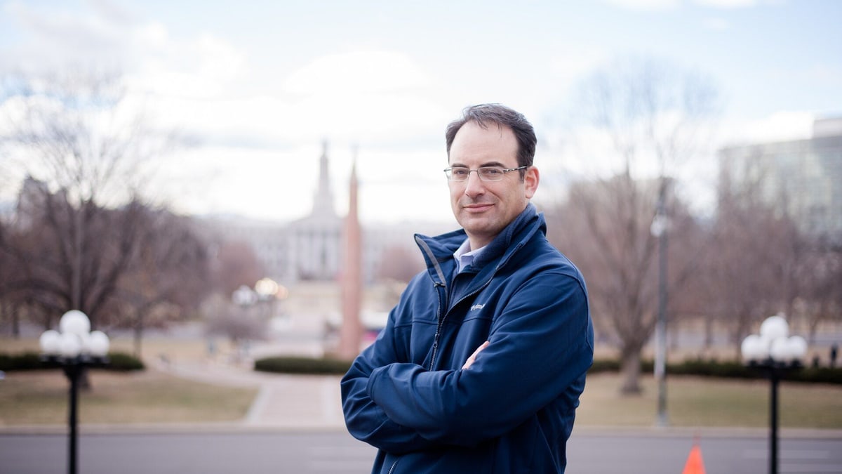 Colorado Attorney General Phil Weiser, who led the states' filing, standing with arms folded outside in Denver
