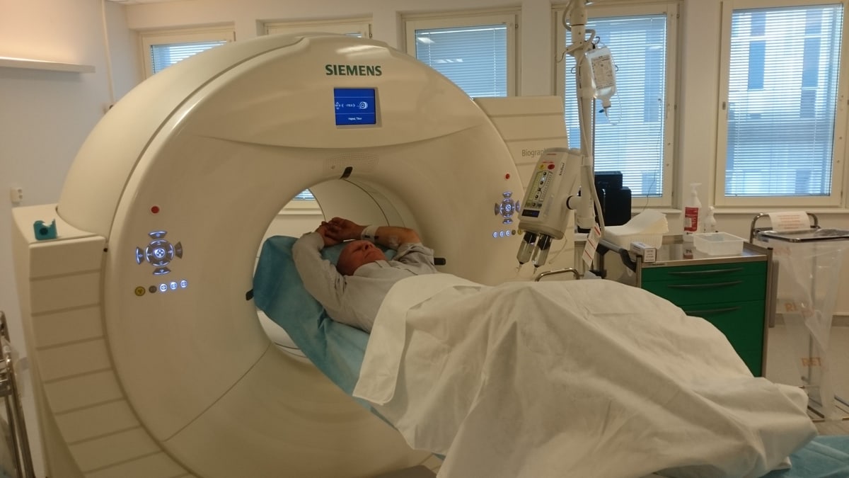 A patient lying in a hospital PET-CT scanner, a machine that takes detailed pictures inside the body, in an imaging room
