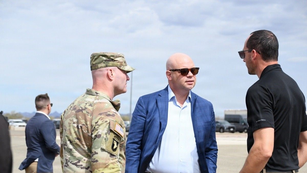 Acting Army Secretary Adam Telle, center in a blue jacket, talks with a soldier and a civilian at Yuma Proving Ground in Arizona
