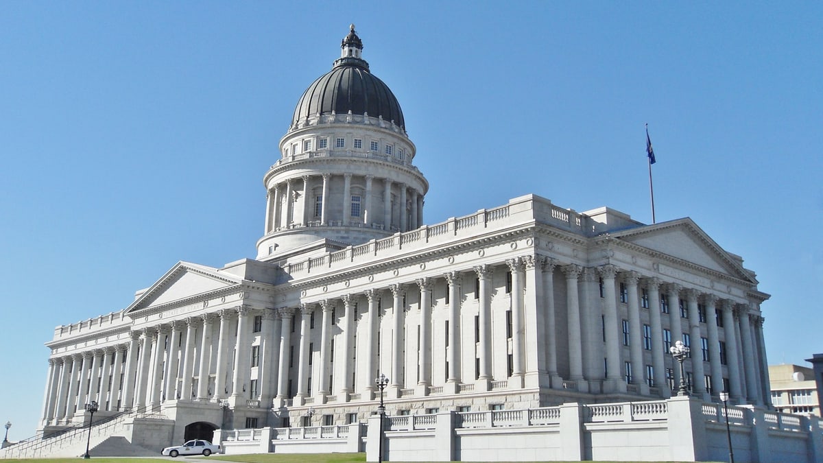 The Utah State Capitol, a white columned building with a gray dome, under a clear blue sky in Salt Lake City