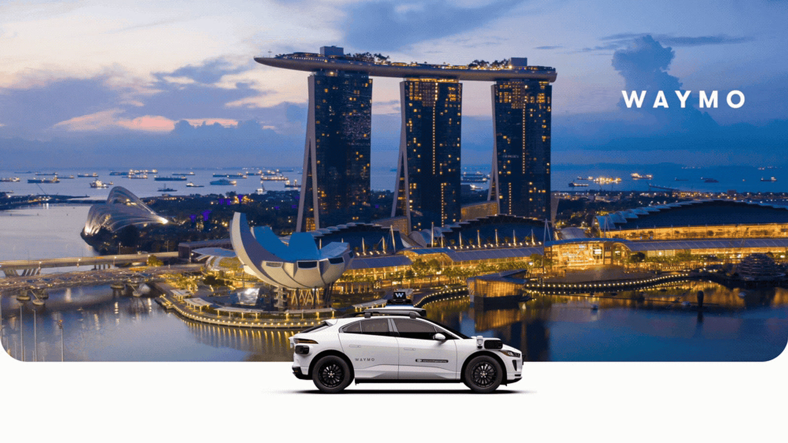White Waymo Jaguar I-PACE autonomous vehicle in front of the Singapore Marina Bay skyline at dusk