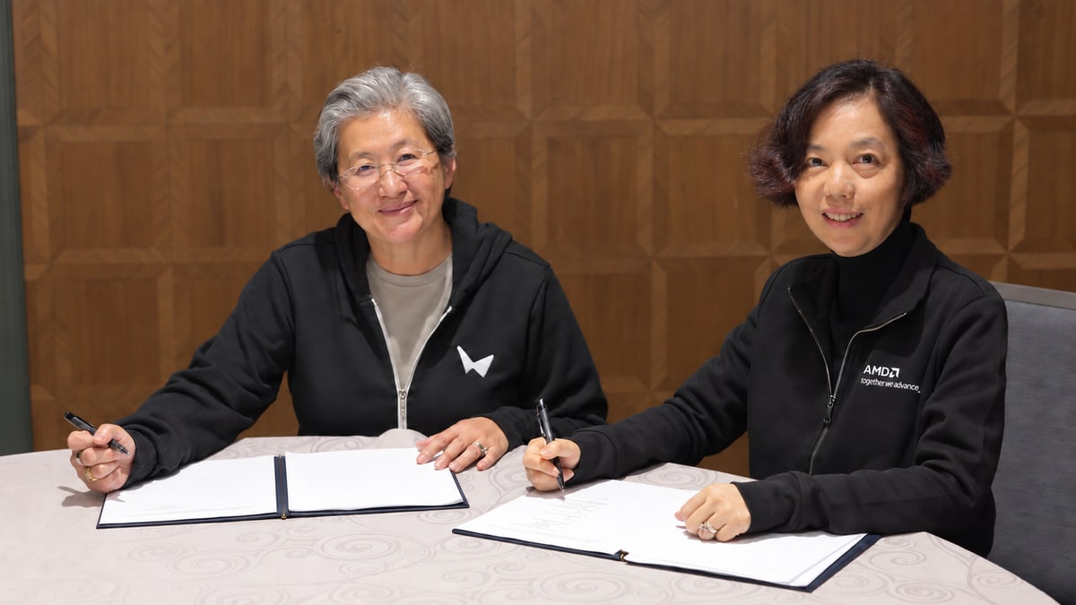 AMD chief executive Lisa Su, left, in a World Labs hoodie, and World Labs chief executive Fei-Fei Li, in an AMD jacket, signing papers at a table