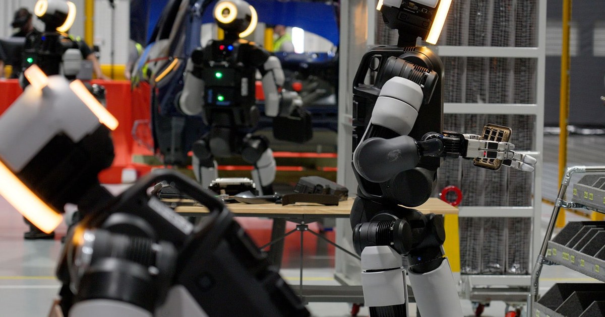 Multiple Atlas humanoid robots working at stations inside the Boston Dynamics RMAC training center