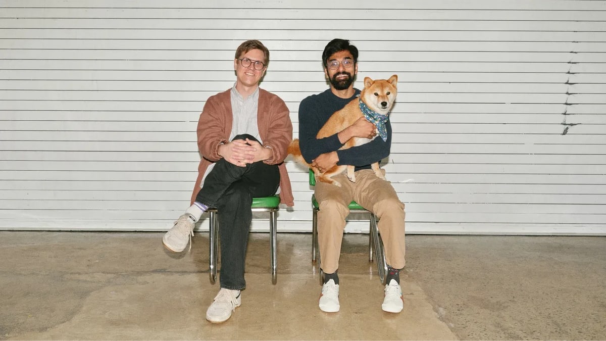 Modal's founders, Erik Bernhardsson and Akshat Bubna, sitting side by side on green chairs in front of a white wall, one of them holding a dog